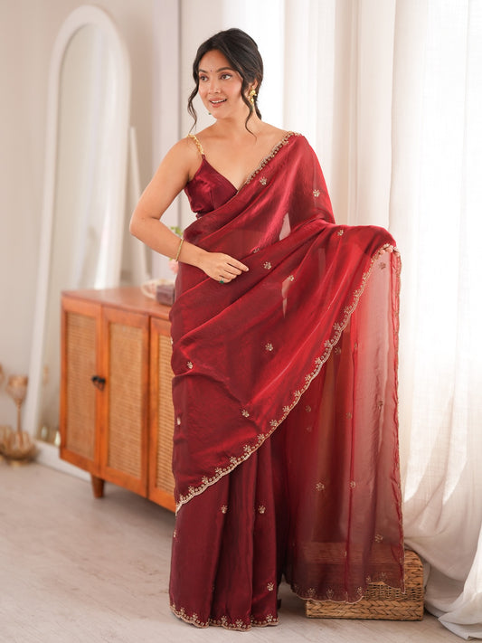 Woman wearing maroon satin saree with ornamented surface design and maroon blouse