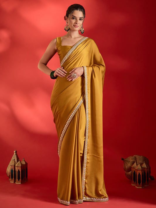 Woman wearing mustard satin saree with clean solid-tone finish and mustard blouse