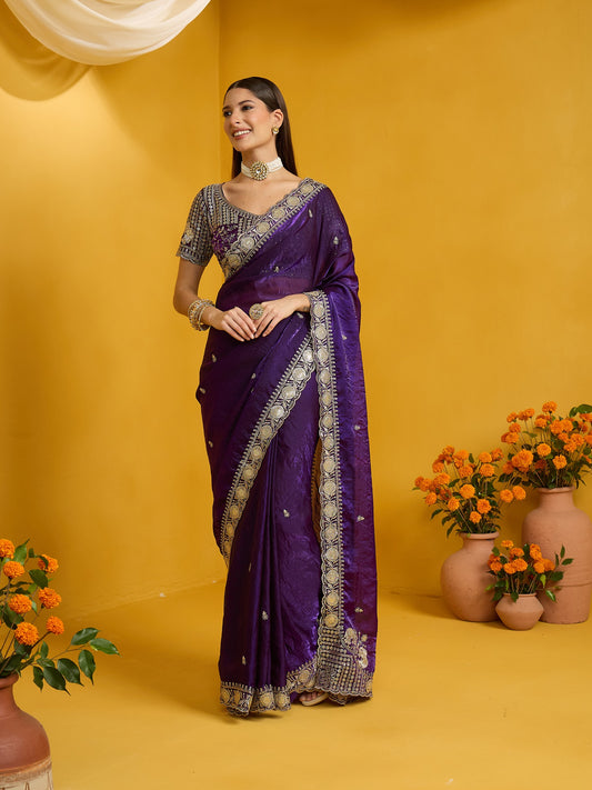 Woman wearing purple satin silk saree with ornamented surface design and purple blouse