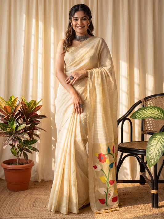 Woman wearing cream muga silk saree with all-over floral design and cream blouse