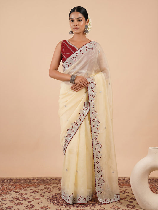 Woman wearing off white tissue saree with embroidered motif work and maroon blouse