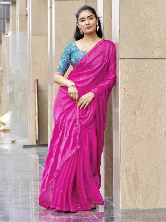 Woman wearing pink satin silk saree with ornamented surface design and turquoise blue blouse
