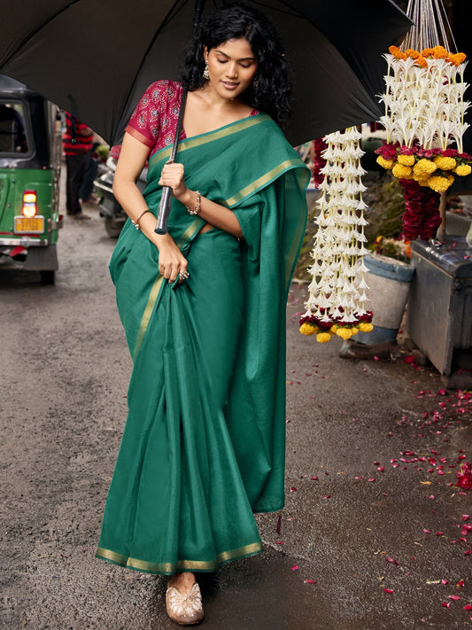 Woman wearing teal green cotton blend saree with clean solid-tone finish and pink blouse