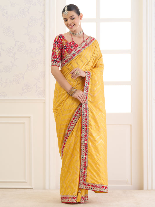 Woman wearing yellow dola silk saree with metallic foil print work and red blouse