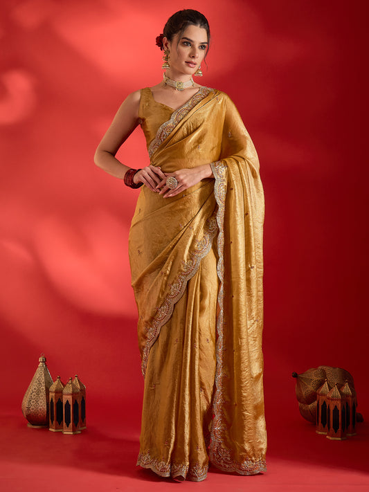 Woman wearing mustard satin saree with ornamented surface design and mustard blouse