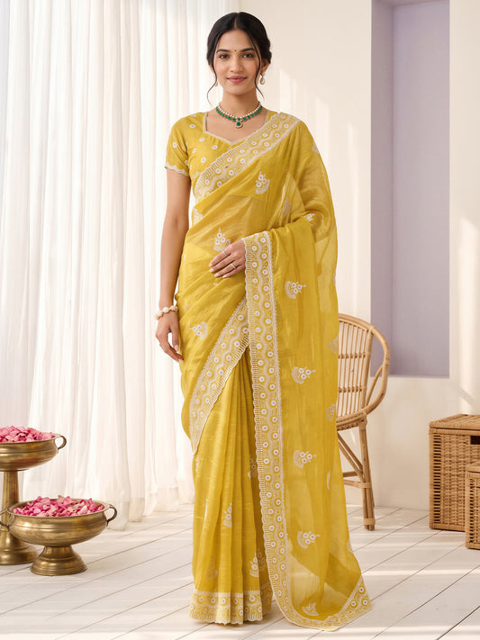 Woman wearing yellow paper silk saree with ornamented surface design and yellow blouse