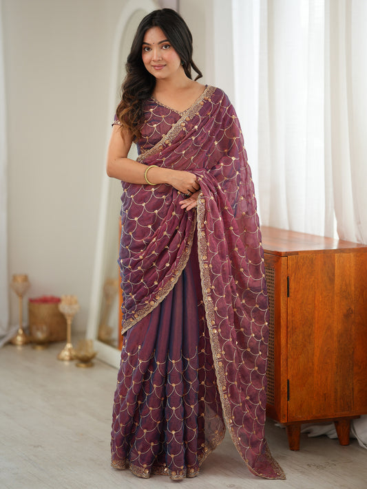 Woman wearing wine tissue saree with ornamented surface design and wine blouse