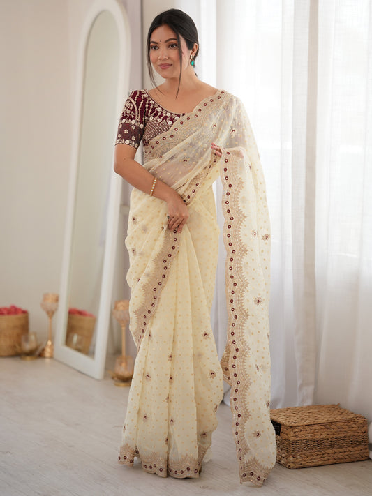 Woman wearing white silk blend saree with ornamented surface design and maroon blouse