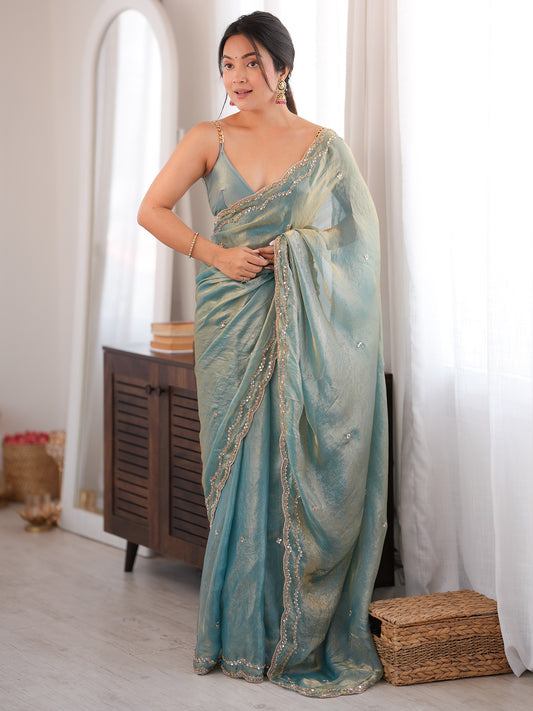 Woman wearing light blue satin silk saree with ornamented surface design and light blue blouse