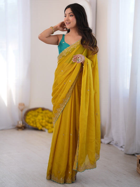 Woman wearing yellow georgette saree with ornamented surface design and turquoise blouse