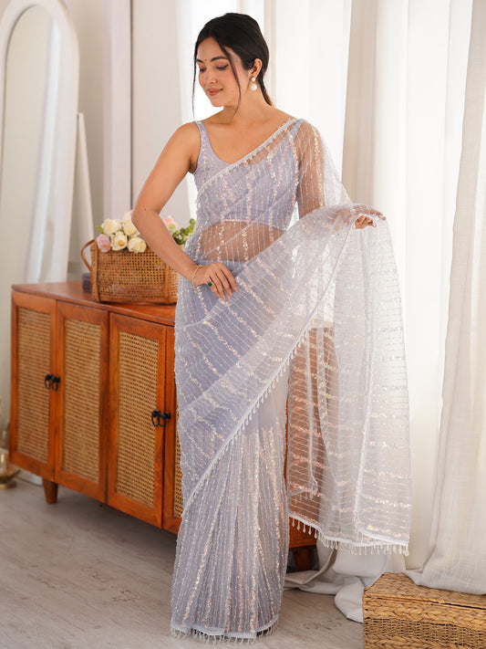 Woman wearing lavender net saree with ornamented surface design and lavender blouse