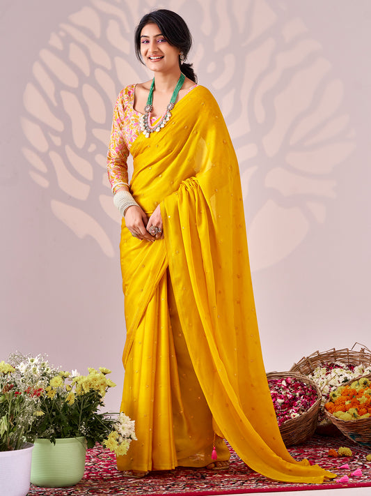 Woman wearing yellow chiffon saree with ornamented surface design and yellow blouse