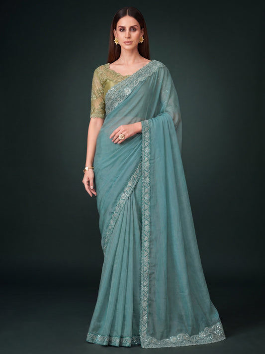 Woman wearing turquoise pure georgette saree with embroidered motif work and green blouse