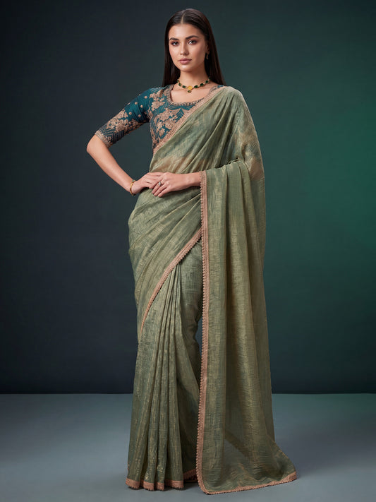 Woman wearing light green georgette saree with ornamented surface design and teal green blouse