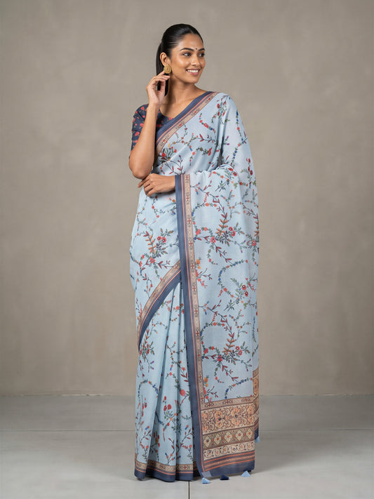 Woman wearing light blue linen blend saree with botanical floral and leaf design and navy blue blouse
