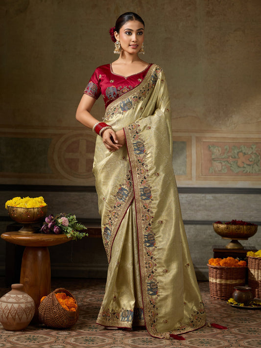 Woman wearing gold silk blend saree with ornamented surface design and maroon blouse