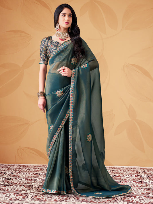 Woman wearing teal blue tissue saree with ornamented surface design and teal blue blouse