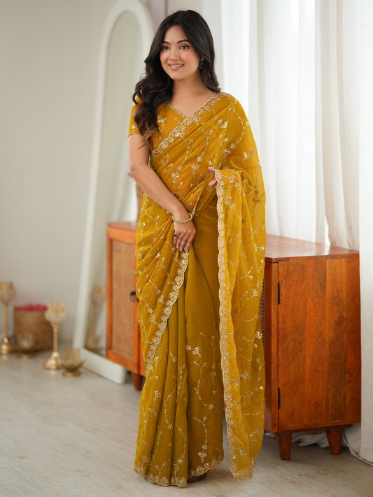 Woman wearing mustard tissue saree with ornamented surface design and mustard blouse