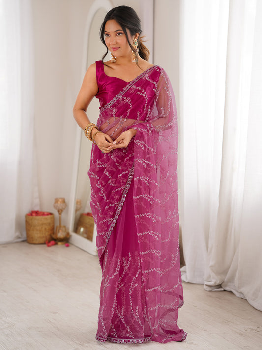 Woman wearing magenta net saree with ornamented surface design and magenta blouse