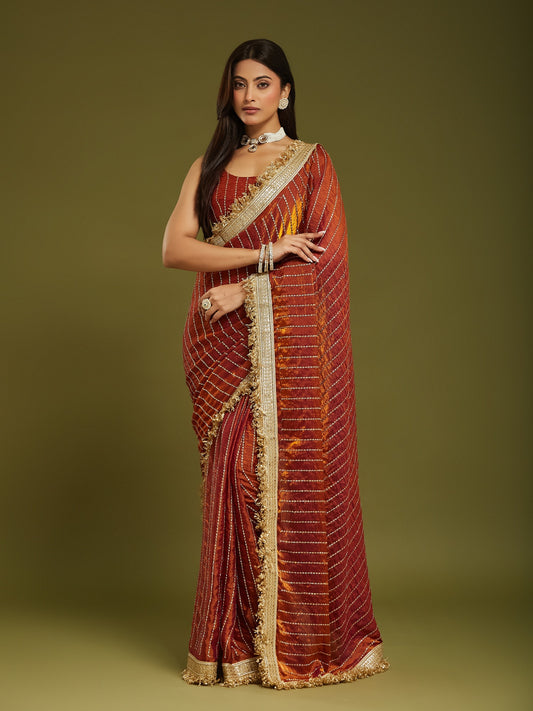Woman wearing orange satin saree with ornamented surface design and orange blouse