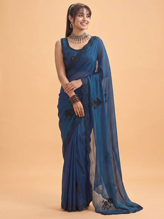 Woman wearing teal blue satin silk saree with ornamented surface design and teal blue blouse