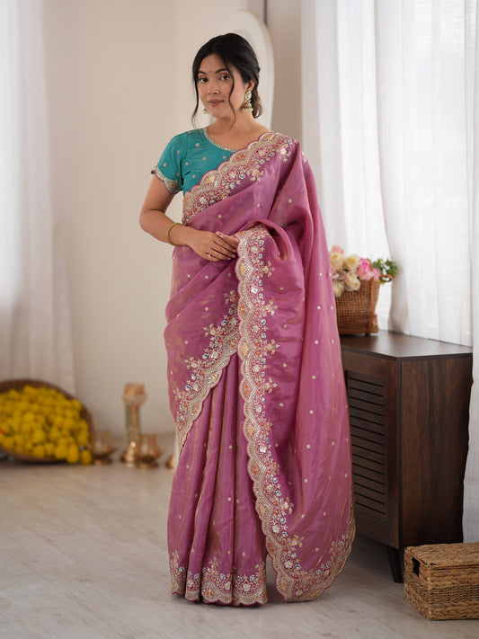 Woman wearing mauve satin saree with ornamented surface design and teal blue blouse