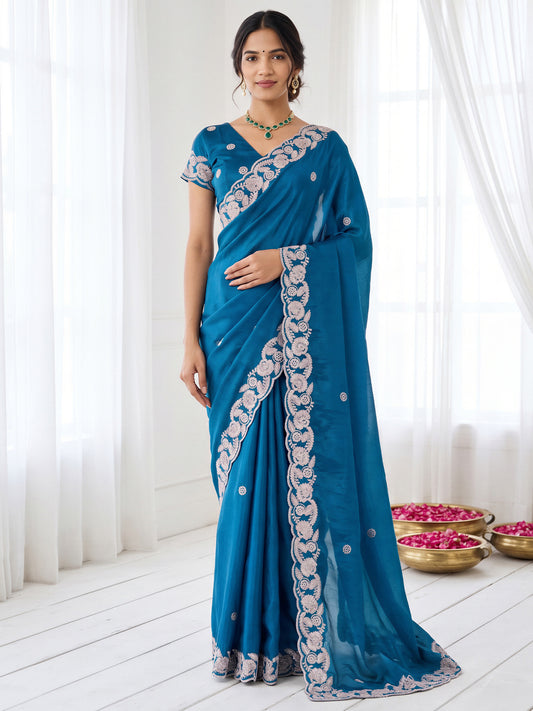 Woman wearing teal blue satin saree with embroidered motif work and teal blue blouse