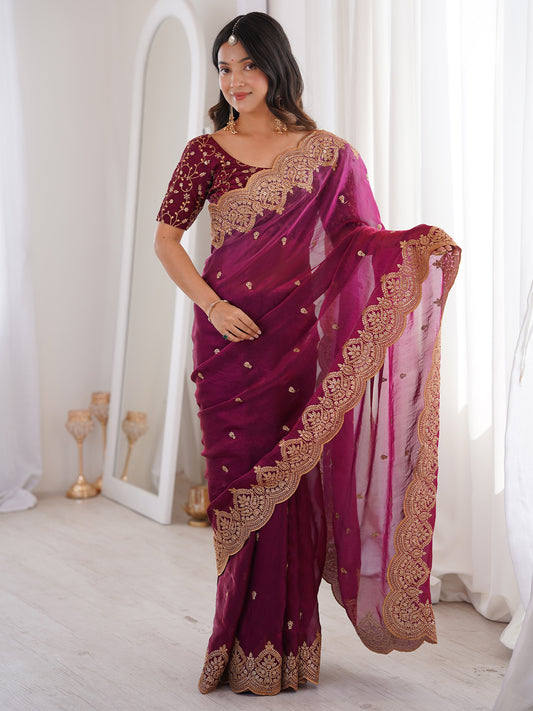 Woman wearing magenta satin saree with ornamented surface design and magenta blouse
