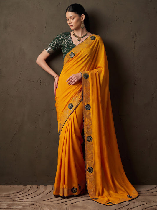 Woman wearing mustard vichitra silk saree with ornamented surface design and green blouse