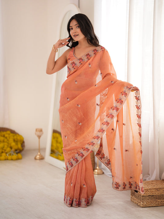Woman wearing peach tissue saree with all-over floral design and peach blouse