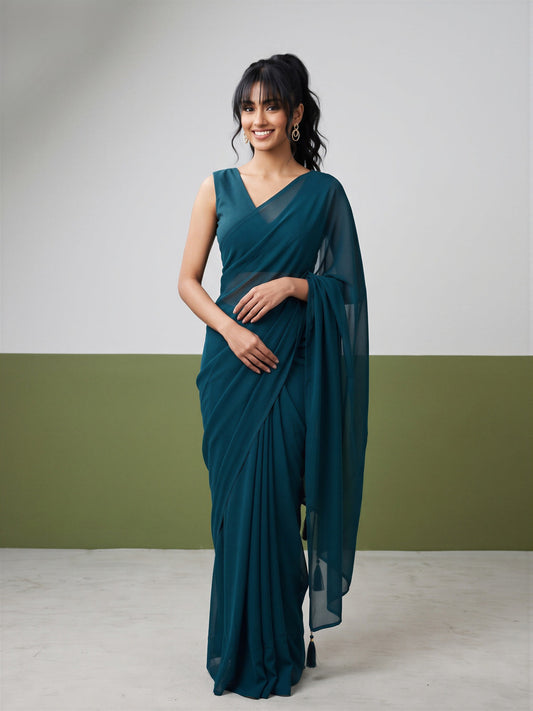 Woman wearing teal green georgette saree with clean solid-tone finish and teal green blouse