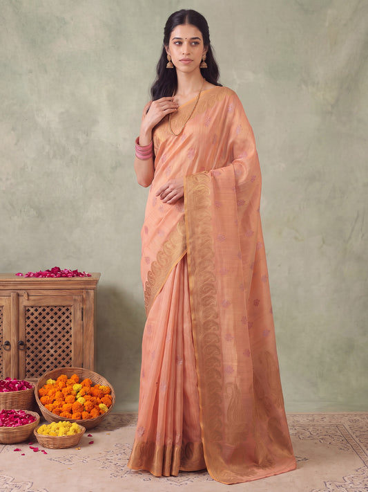 Woman wearing peach linen saree with traditional indian motif work and peach blouse