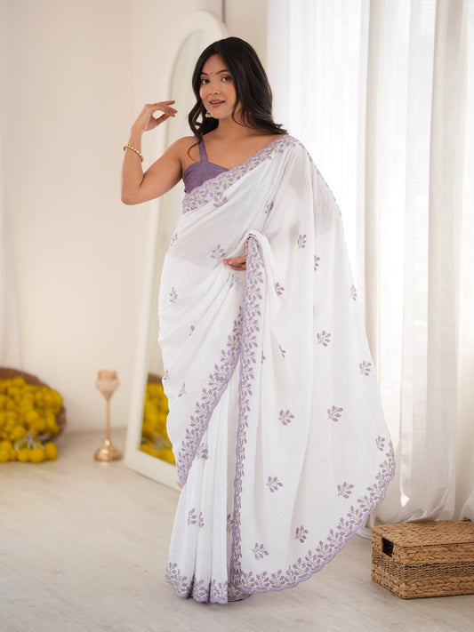 Woman wearing white poly georgette saree with ornamented surface design and purple blouse