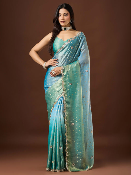 Woman wearing light blue satin saree with ornamented surface design and light blue blouse