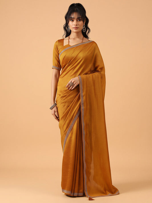 Woman wearing mustard satin silk saree with ornamented surface design and mustard blouse