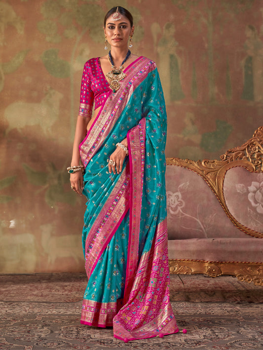 Woman wearing turquoise blue silk blend saree with traditional indian motif work and pink blouse