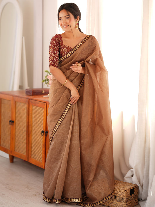 Woman wearing copper tissue saree with clean solid-tone finish and brown blouse