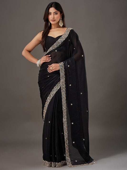 Woman wearing black satin saree with ornamented surface design and black blouse