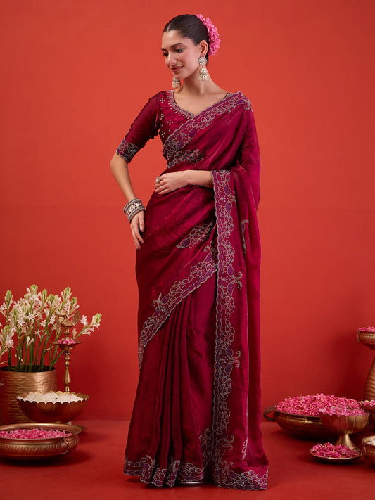 Woman wearing magenta satin saree with ornamented surface design and magenta blouse