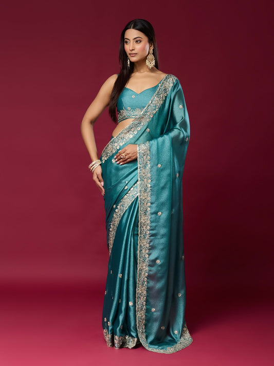 Woman wearing teal blue chinnon saree with embroidered motif work and teal blue blouse
