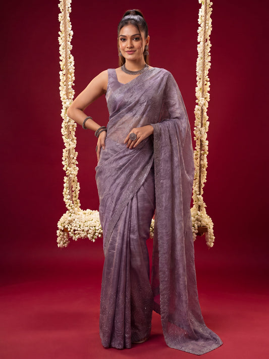 Woman wearing lavender tissue saree with ornamented surface design and lavender blouse