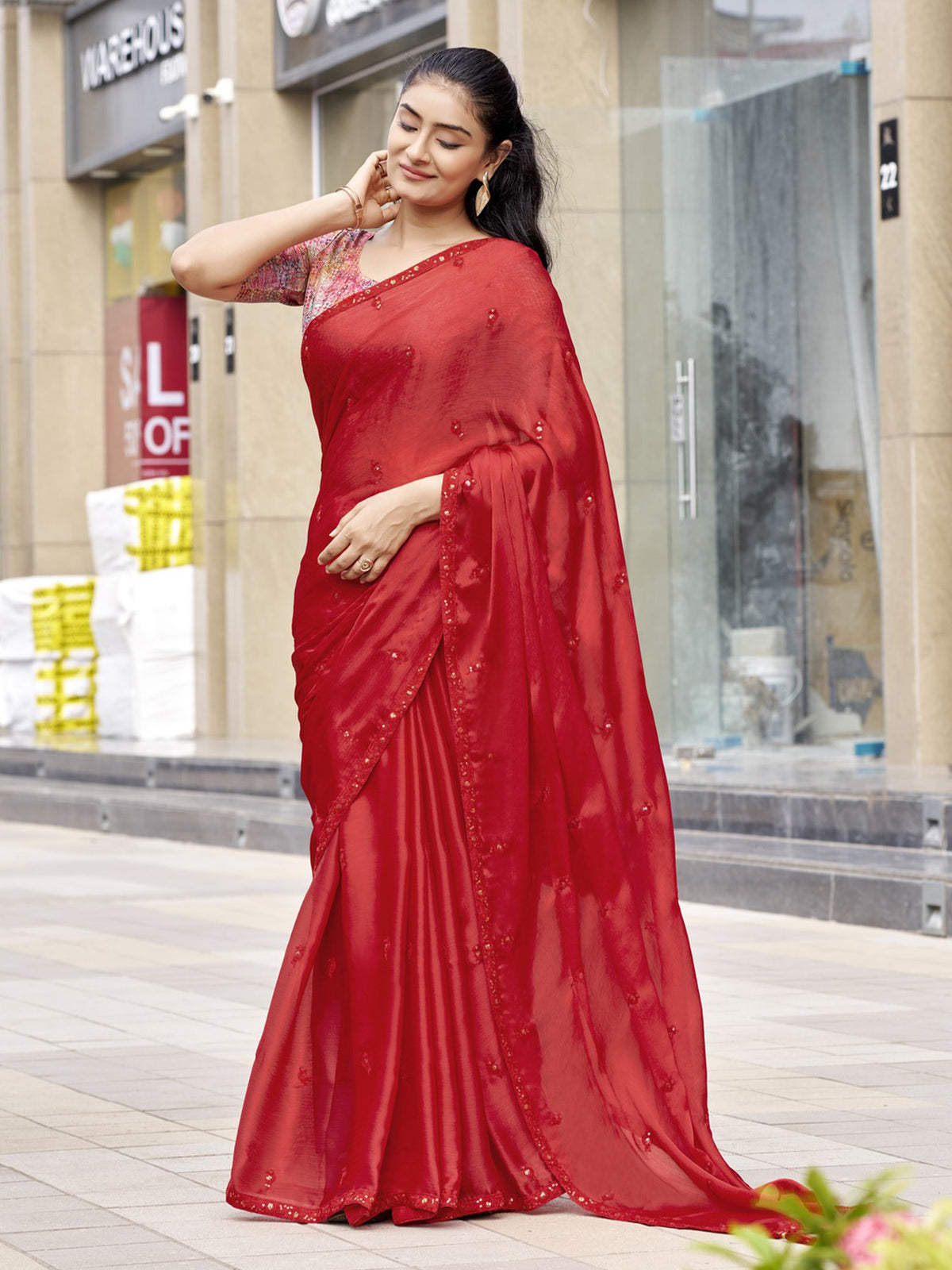 Woman wearing red satin silk saree with ornamented surface design and multicolored blouse
