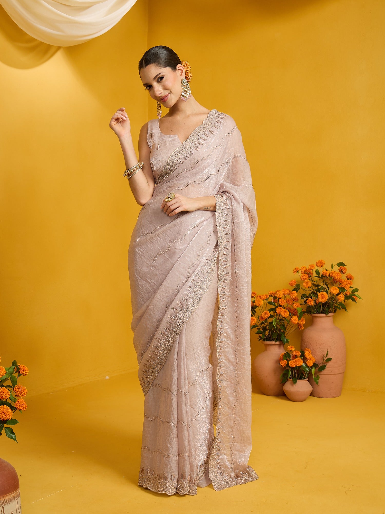 Woman wearing beige satin silk saree with ornamented surface design and beige blouse