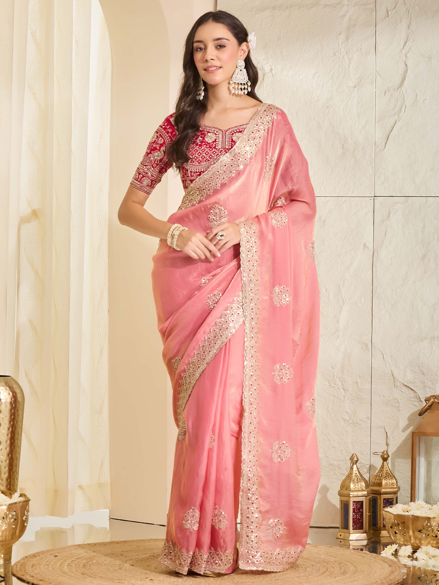 Woman wearing peach satin saree with ornamented surface design and red blouse