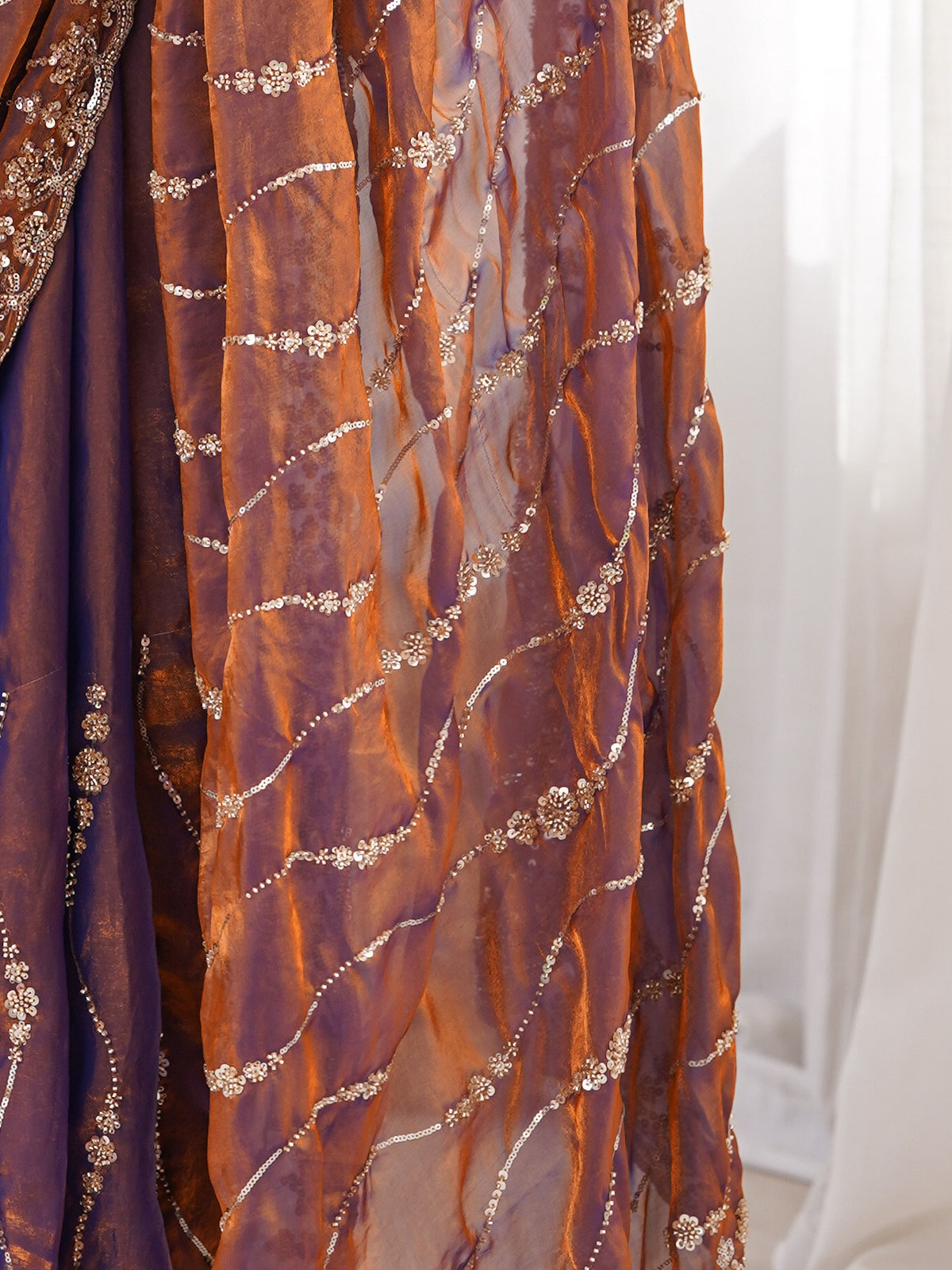 Pallu detail of bronze satin saree showing ornamented surface design and embellished border