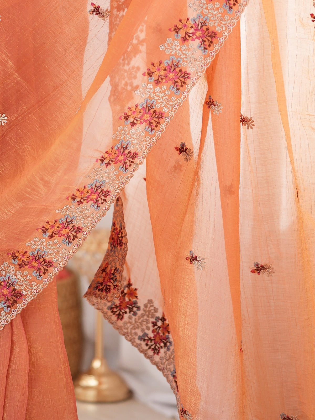 Pallu detail of peach tissue saree showing all-over floral design and embroidered border