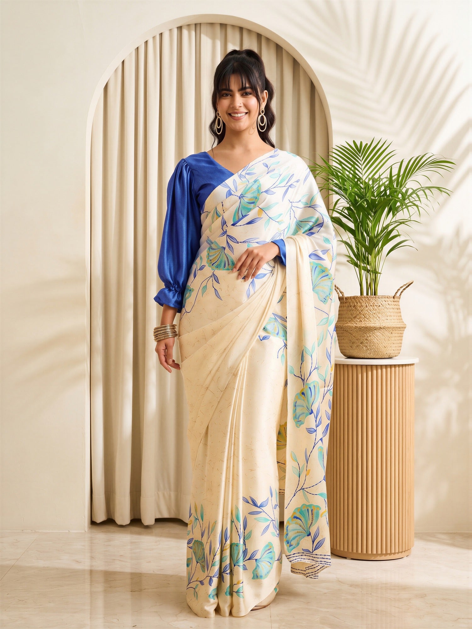 Woman wearing beige satin saree with botanical floral and leaf design and blue blouse