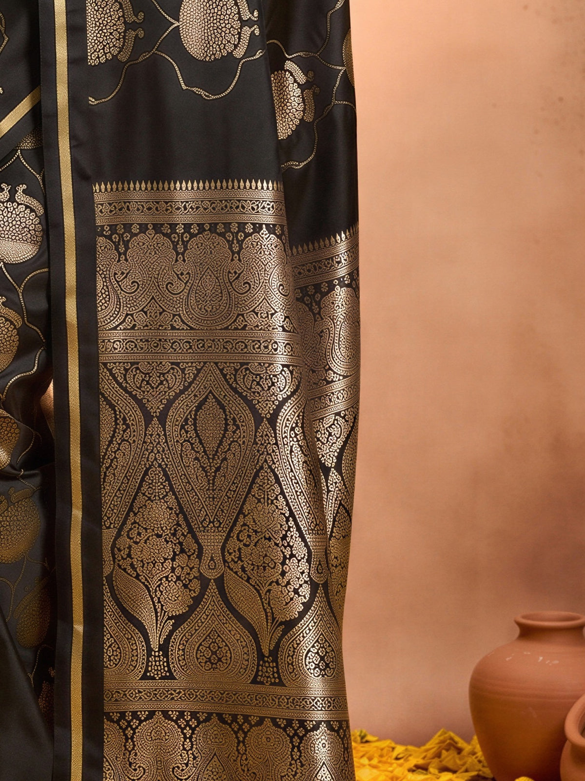 Pallu detail of black satin saree showing zari butta (metallic motif) work and zari border