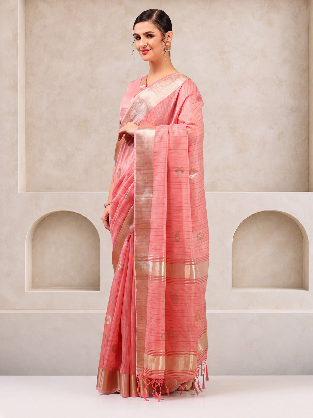 Woman wearing pink linen saree with zari butta (metallic motif) work and pink blouse