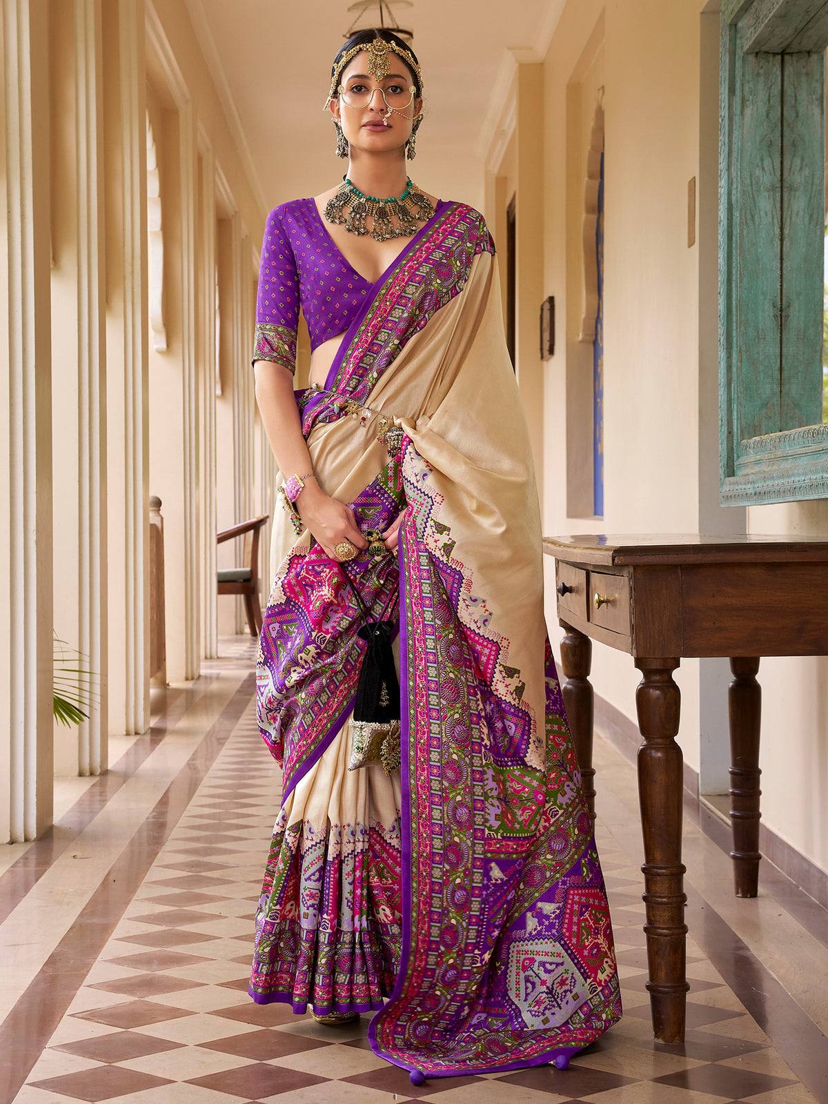Woman wearing beige silk blend saree with traditional indian motif work and violet blouse